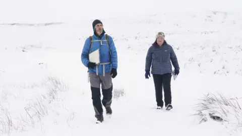 PA Media Man and woman walking in snow