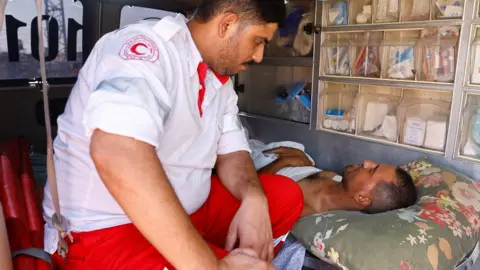 Reuters A medic speaks to an injured Palestinian inside an ambulance at Gaza's Rafah border crossing with Egypt (1 November 2023)