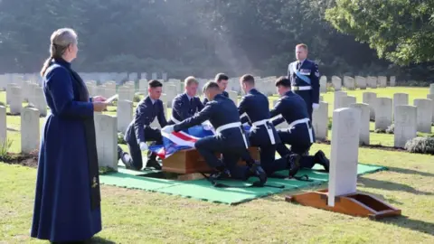 MOD The RAF's Queen's Colour Squadron (QCS) remove the Union Flag from Flt Sgt Hurrell's coffin before laying him to rest