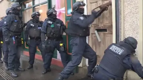 South Wales Police Police carrying out one of several raids in south Wales