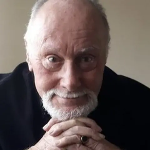 Peter Lee Goodchild Peter with his hands clasped under his chin