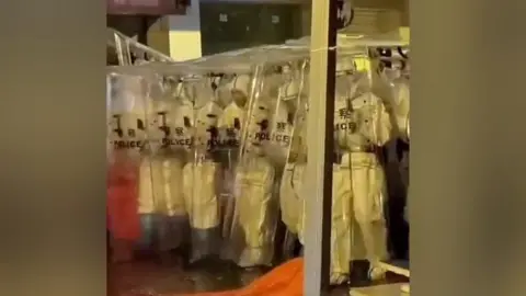 Riot police in hazmat suits