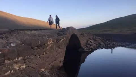 People walking across the bridge at Spelga Reservoir