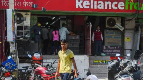 Getty Images Man with shopping bags in front of Reliance grocery store.