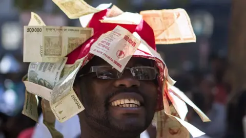 Getty Images A man wearing a hat decorated with worthless note bearers' cheques during a protest against government plans to introduce bond notes