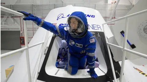 Getty Images Boeing propulsion engineer Monica Hopkins climbs out of a mockup of the CST-100 Starliner crew module, while wearing a newly-designed spacesuit.