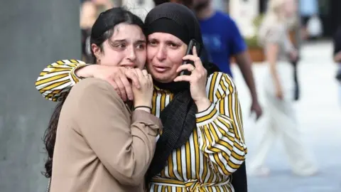 EPA People react in front of the Fields shopping centre during evacuation by armed police