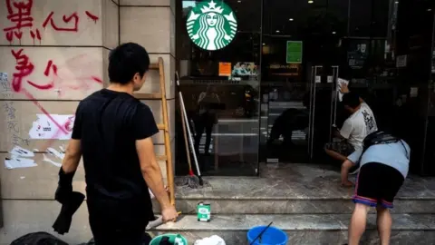 Reuters A worker cleans graffiti at a Starbucks coffee shop in Hong Kong on 30 September