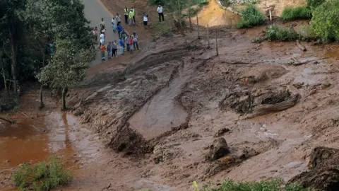 Reuters Residents are seen in an area next to a dam that burst