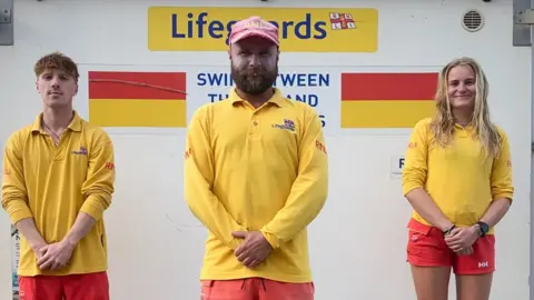 Tom Davis Three life guards (two men and one woman) in yellow shirts