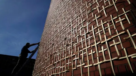 Clodagh Kilcoyne/Reuters A man attaches crosses to the wall of an outdoor chapel