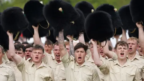 PA Media Members of the Welsh Guards remove their head dress