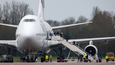 PA Media Passengers disembark a plane from Wuhan