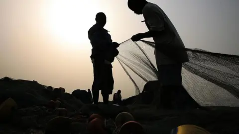 Getty Images Fishermen prepare their fishing nets in Accra.