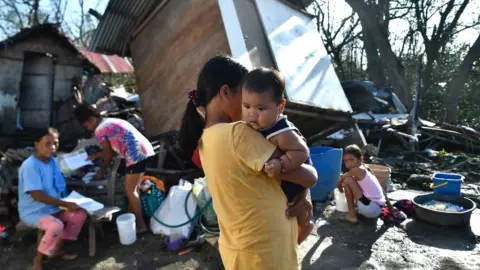 AFP Residents gather next to their destroyed house in Carcar, Philippines' Cebu province on December 18, 2021, days after Super Typhoon Rai hit the city