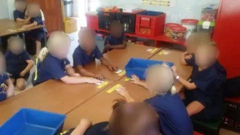 . Black and white children sit together in mixed groups in South Africa