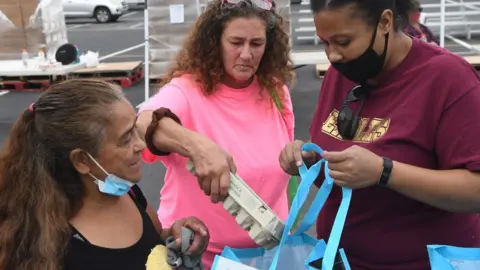 Getty Images A volunteer hands out assistance for laid off Walt Disney World cast members and others at a food distribution event on December 12, 2020 in Orlando, Florida