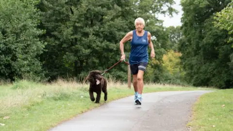 PA Media Caroline Quibell running with her Irish water spaniel Streak