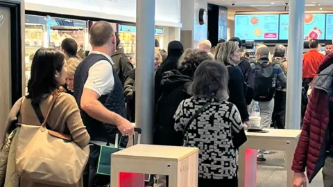 Kerry Hamilton A long queue of people at a sandwich shop