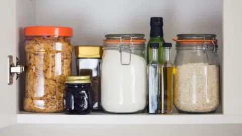 Getty Images Image shows food including jam, cereal and rice in a cupboard