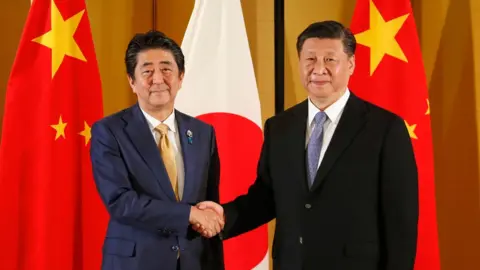 AFP Japanese Prime Minister Shinzo Abe (R) shakes hands with Chinese President Xi Jinping