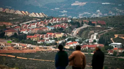 Getty Images People stand in front of the Jewish settlement of Shvut Rachel during a tour organised by the Palestinian authorities for ambassadors based in Tel Aviv and consuls based in Jerusalem on March 16, 2017