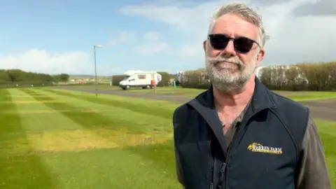 Paul Bowkett from Warren Farm Holiday Park standing in front of his pitches