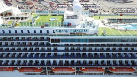 Getty Images Passengers look out as the Grand Princess cruise ship docks at the Port of Oakland in Oakland, California on 9 March, 2020