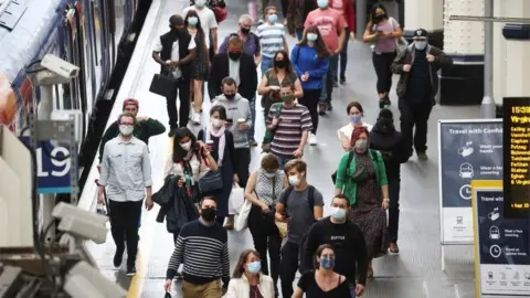 Reuters People, some wearing protective face masks, walk through Waterloo Station