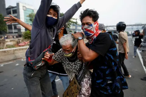 Willy Kurniawan / Reuters Demonstrators in Jakarta cover an elderly woman during clashes with police