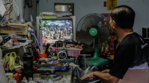 Getty Images A man is pictured watching the news of the boys' rescue on a television in nearby Chiang Rai