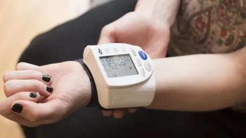 Science Photo Library Woman takes her blood pressure at home