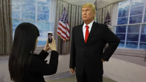 Getty Images A Chinese visitor taking a photo of a wax figure of US President Donald Trump in Shenyang, northeastern China's Liaoning province