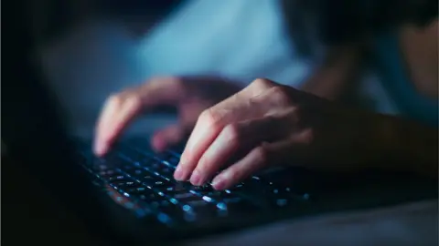 A close-up of female hands typing on a keyboard