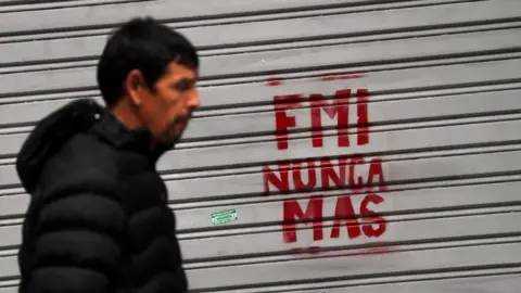 Reuters Man walks past graffiti reading "IMF never again" in Buenos Aires, 1 June 2018