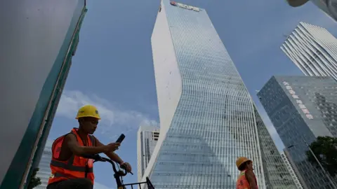 AFP Workers walk in front of the Evergrande headquarters in Shenzhen, southeastern China on September 26, 2021.