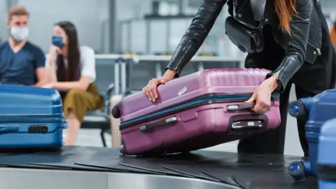 Getty Images/izusek Suitcases on a baggage carousel