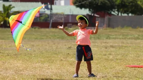 Reuters A boy flies a rainbow-coloured kite.