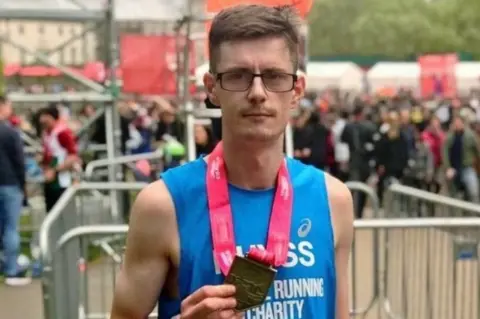 Family photo Rhyss holding medal after half marathon