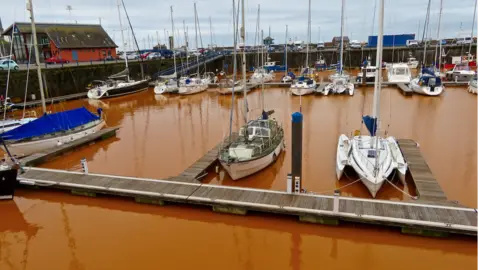 Marianne Birkby Boats in orange water at Whitehaven Harbour