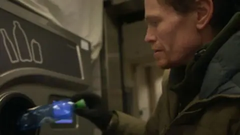 Man recycling plastic at bottle bank