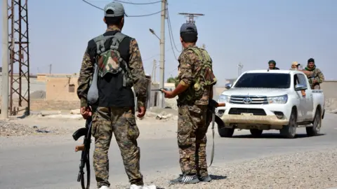 EPA Syrian Democratic Forces fighters stand guard on the outskirts of Raqqa, Syria (11 June 2017)