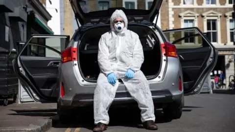 Getty Images Uber driver Yasar Gorur wears personal protective equipment while cleaning his vehicle