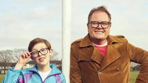 ITV Oliver Savell and Alan Carr pose on a football pitch in a promotional image for Changing Ends