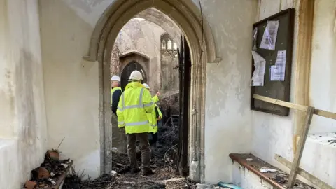 Jill Bennett/BBC Villagers looking inside the church