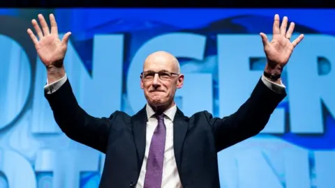 PA Media John Swinney holds his hands up in celebration