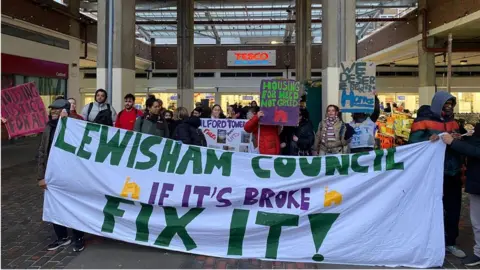 Lilly Croucher/BBC Protesters holding placards and a banner