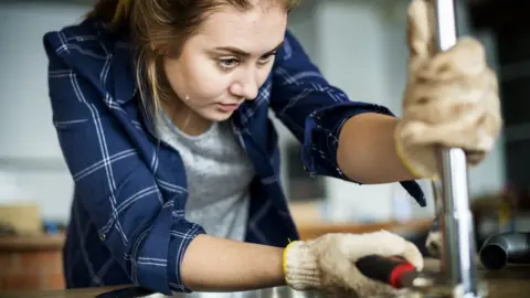 Getty Images Woman fixing kitchen tap