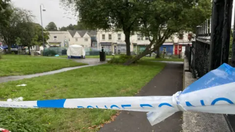 BBC A police cordon and a forensic scene tent in a park in Bristol