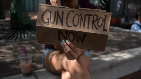 Getty Images A woman holds a placard that say gun control now during a gun reform rally that was held in Dayton, Ohio in the wake of a mass shooting at the area earlier this month that left 9 dead and 27 wounded.